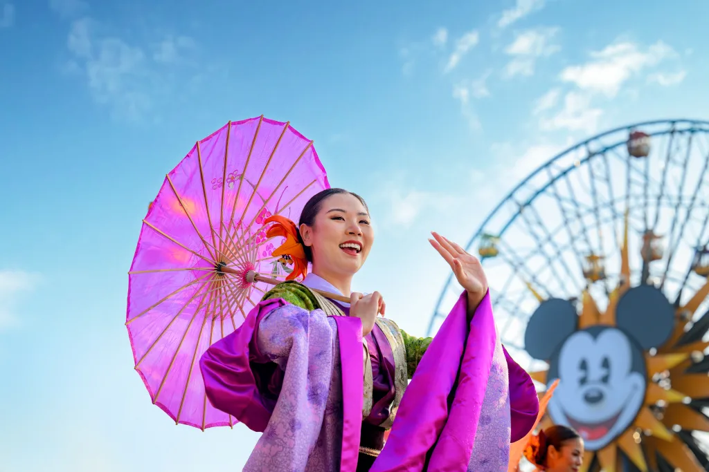 カリフォルニア ディズニーランド・リゾートの季節イベントで中国衣装のパフォーマーが踊る様子と観覧車の写真